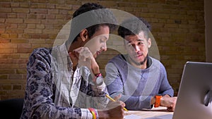 Closeup shoot of indian and african american male students using the laptops and discussing a school project sitting