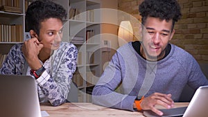 Closeup shoot of indian and african american male students using the laptops and discussing a school work sitting