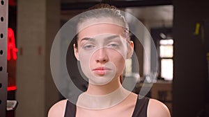 Closeup shoot of young attractive athlete female getting ready to workout looking at camera in the gym indoors