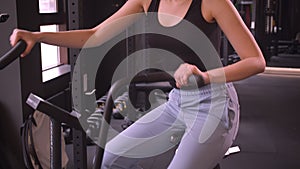 Closeup shoot of young attractive athlete healthy female with ponytail working out on the orbitrek being motivated and