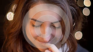 Closeup shoot of young attractive caucasian female smiling seductively and biting her lip in front of the camera with