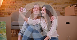 Closeup shoot of young beautiful lesbian couple bloggers talking on camera streaming live on the phone hugging and