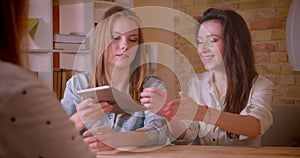 Closeup shoot of young beautiful lesbian couple talking to female realtor with the tablet about purchase of an apartment