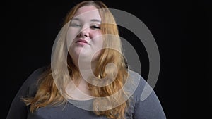 Closeup shoot of young overweight caucasian female looking at camera and smiling seductively with background isolated on