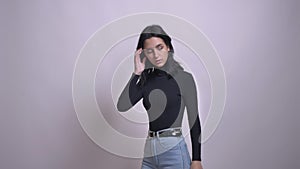 Closeup shoot of young pretty caucasian black-haired female in stylish jeans looking at camera and posing