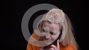 Closeup shoot of young pretty caucasian female having a casual conversation on the phone in front of the camera