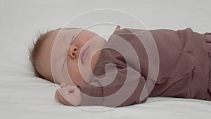 Closeup Shot Of Adorable Newborn Baby Peacefully Sleeping On Bed At Home