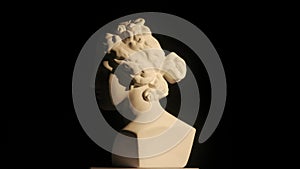 Closeup shot. Ancient marble bust statue of roman era woman spinning round on a platform. Isolated on black background