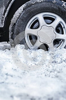 Closeup shot of an automobile wheel stuck in deep snow
