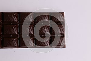 Closeup shot of a bar of dark chocolate isolated on a white background