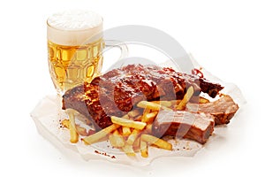 Closeup shot of barbeque pork spareribs and French fries served with a glass of lager beer