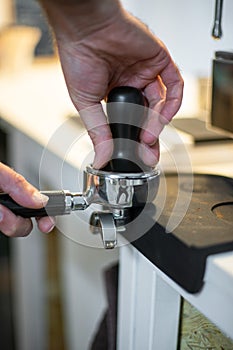 Closeup shot of a bartend holding a coffee tamper and compressing coffee grounds