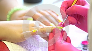 Closeup shot of a beautician applying nail polish to female nail in a nail salon. Close up of a woman hand with yellow