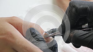 Closeup shot of a beautician applying nail polish to female nail in a nail salon. Woman getting nail manicure, spa