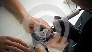 Closeup shot of a beautician applying nail polish to female nail in a nail salon. Woman getting nail manicure, spa