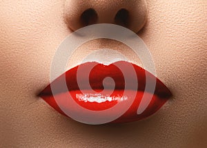 Closeup shot of beautiful full lips with red glossy make-up. Perfect bright lipstick. Plastic surgery or makeup concept