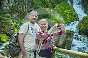 Closeup shot of a beautiful loving couple in nature with a waterfall on the background