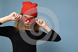 Closeup shot of beautiful sexy young dark blonde curly woman isolated over blue background wall wearing casual black