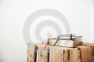 Closeup shot of a bible and notepad on a wooden box with a white background