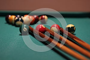 Closeup shot of billiard cues next to the balls on the table