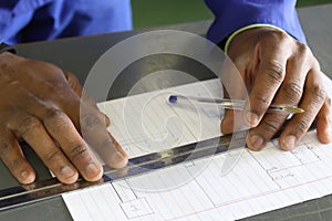 Closeup shot of a black architect's hands designing a building plans on paper