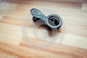 Closeup shot of a black camera lens for mobile phones on the wooden surface