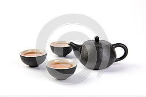 Closeup shot of a black teapot with three teacups isolated on white background