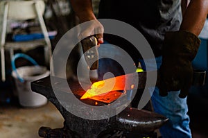 Closeup shot of a blacksmith hammering the glowing red hot steel to make a knife