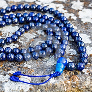 Closeup shot of blue mala beads (lapislazuli) on stone - Yoga and meditation accessory photo