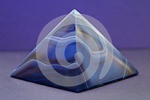 Closeup shot of a blue marble pyramid with a purple background