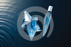 Closeup shot of the blue perfume bottles in dynamic background with water elements