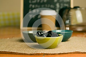 Closeup shot of a bowl of black olives on a wooden table