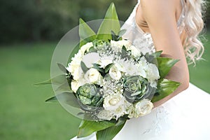 Closeup shot of a bride holding the beautiful wedding bouquet isolated on blurred natural background