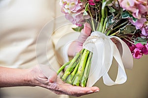 Closeup shot of the bride holding her elegant wedding bouquet with pink and white flowers