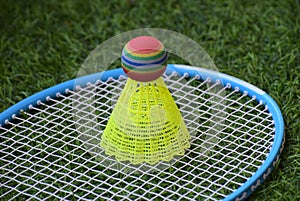 Closeup shot of a bright yellow shuttlecock on a badminton racket