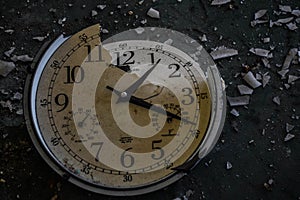Closeup shot of a broken clock with the shards flown apart on the ground photo