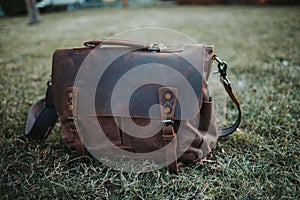 Closeup shot of a brown leather satchel on the green grass