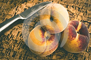 Closeup shot of a bunch of peaches and a steel knife next to them