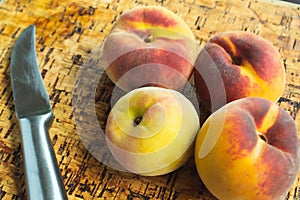 Closeup shot of a bunch of peaches and a steel knife next to them