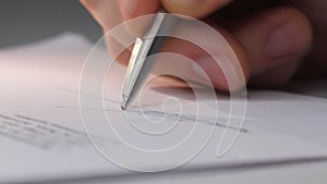 Closeup shot of a business man signing a contract, legal agreement or paper. Man is approve documents by signing papers.