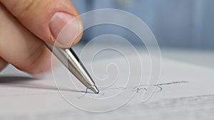 Closeup shot of a business man signing a contract, legal agreement or paper. Man is approve documents by signing papers.