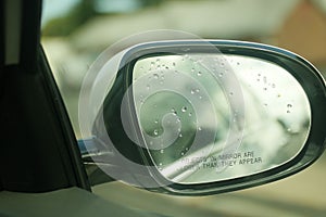 Closeup shot of a car's side-view mirror with rain drops