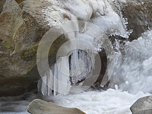 Closeup shot of a cascade of water with white ice melting on the rock