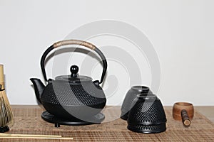 Closeup shot of a cast-iron Japanese teapot, teacups and wooden ladle