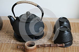 Closeup shot of a cast-iron Japanese teapot, teacups and wooden ladle