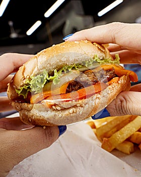 Closeup shot of the cheese burger and fries in the hands