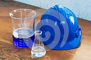 Closeup shot of chemical flasks and a blue helmet