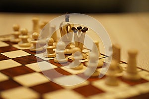 Closeup shot of a chessboard with the focus on white\'s king, queen and pawns