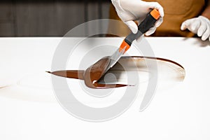 Closeup shot of a chief making delicious tempered chocolate on a white surface