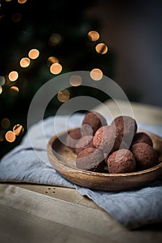 Closeup shot of chocolate round truffles in a wooden bowl on the table. Dessert wallpaper